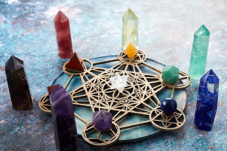 Chakra crystal towers with a central clear quartz arranged on a wooden crystal board grid