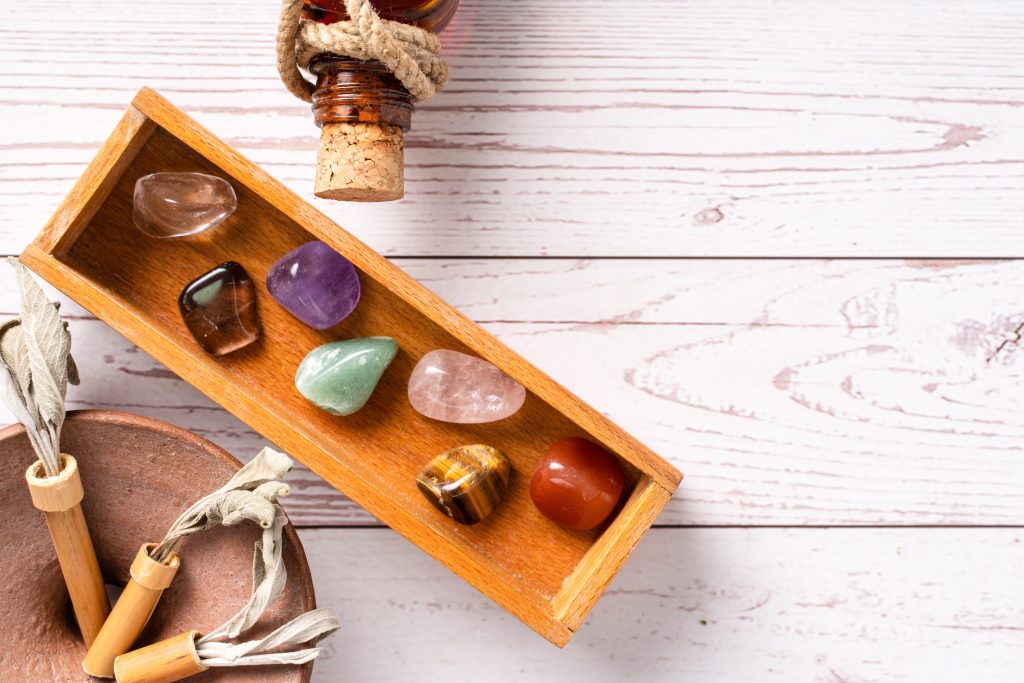 Top down view on seven chakra healing crystal stones for mind body and soul reiki practicing homeopathy alternative medicine on wooden table with copy space