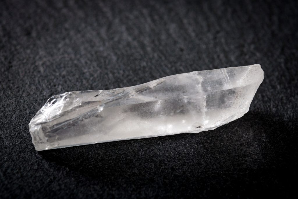 Uncut diamond, white quartz and raw gemstone concept with a white clear mineral stone against a dark background